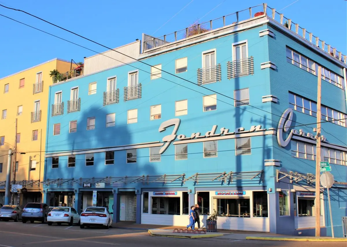 Exterior view of the historic blue Fondren Corner building in Jackson, Mississippi, home to Rooster’s restaurant and the iconic neon sign.