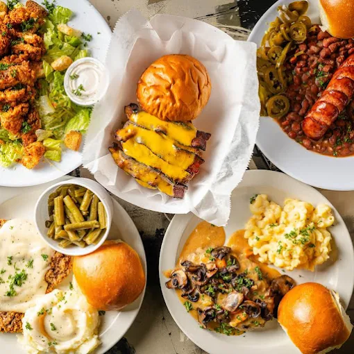 A spread of Southern comfort food from Rooster’s, including country fried steak with gravy, a brisket burger, fried chicken, mac and cheese, and red beans with rice.